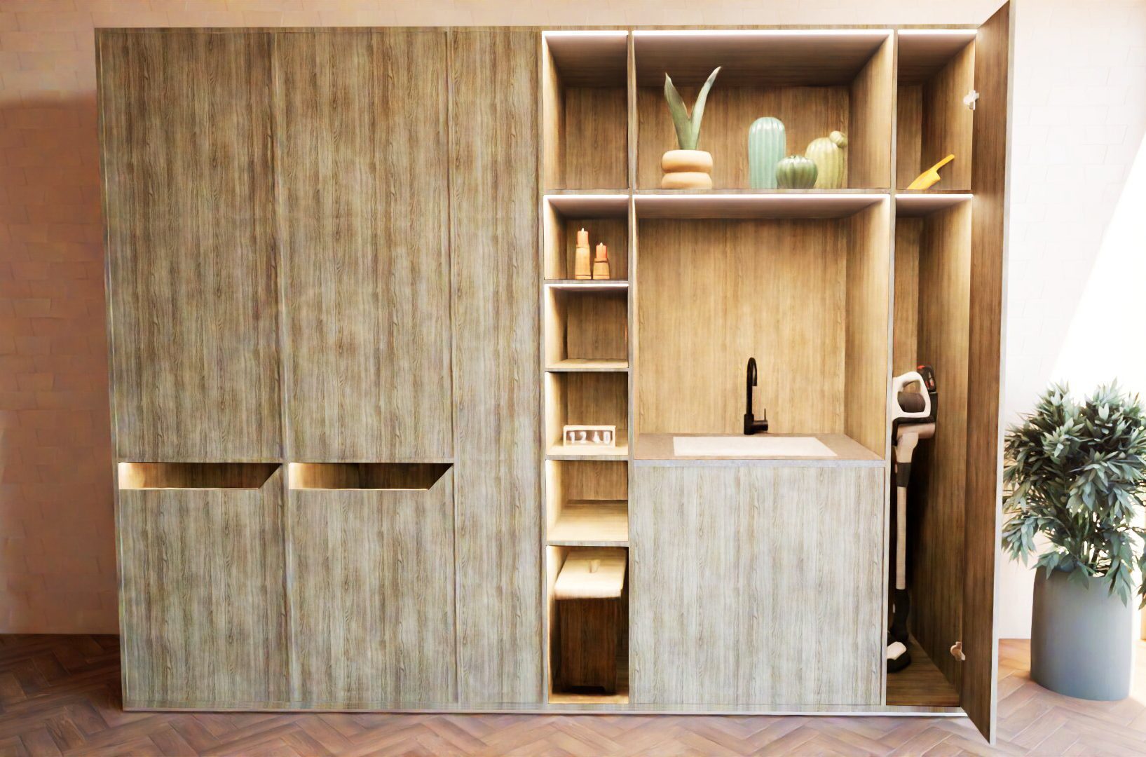 Modern kitchenette with wood panel cabinets, open shelves displaying decor and toiletries, a sink, and a vacuum cleaner stored on the right side; potted plant on the floor nearby.